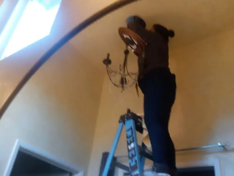 Electrician installing a chandelier in a Delhi residence